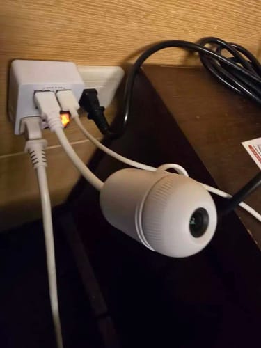 El proyector enchufado al lado de la cama con su cuello flexible