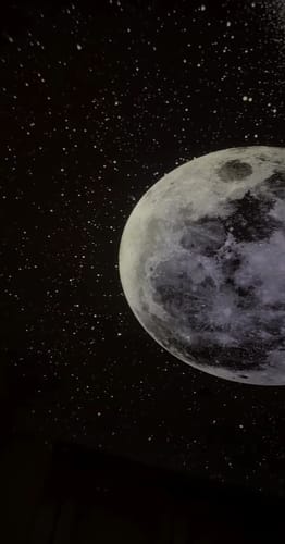 Luna proyectada entre estrellas en el techo de la pieza